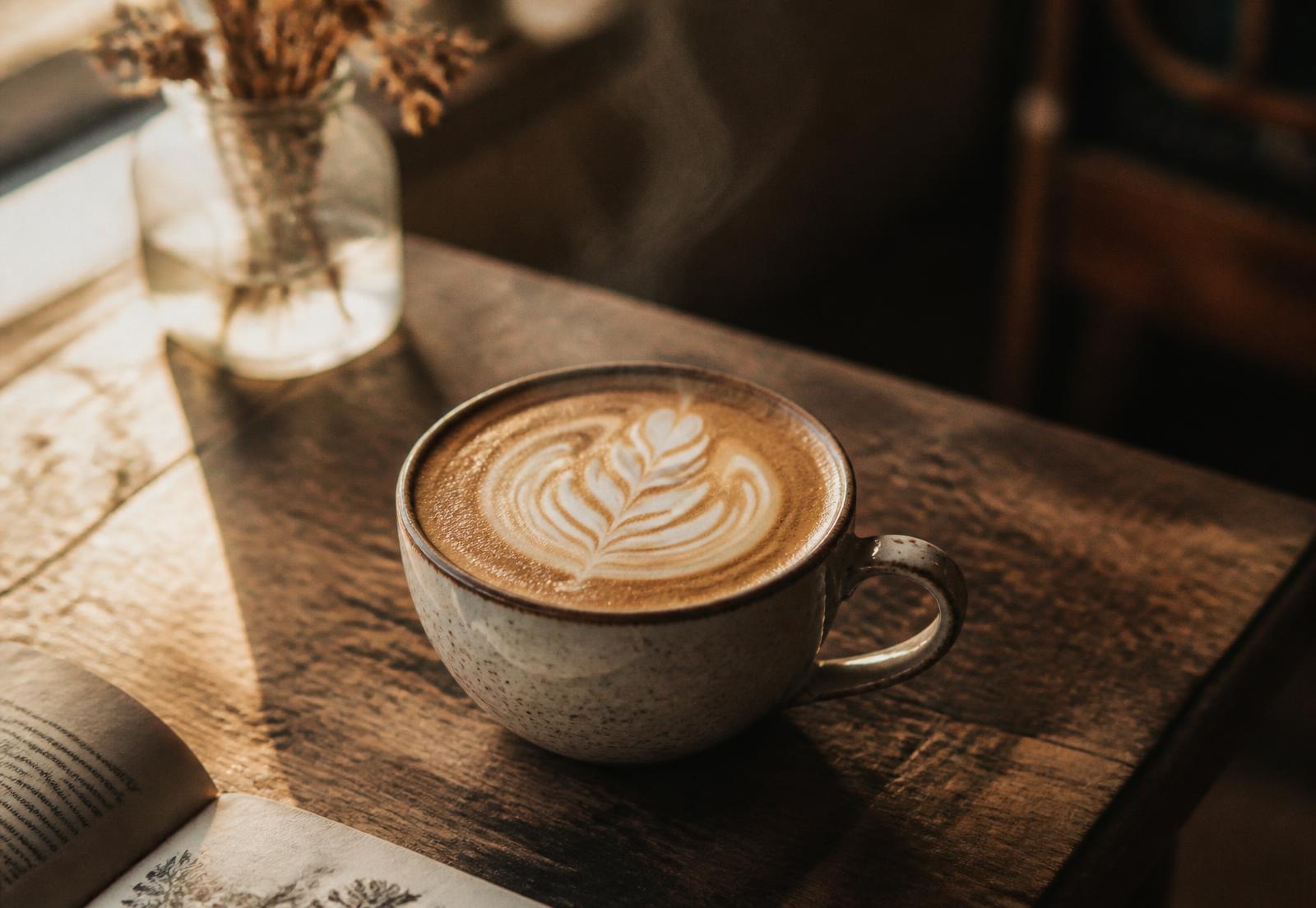 Latte with rosetta art on a wooden cafe table in warm morning light
